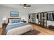 Staged bedroom with hardwood floors features a bed, rug, open closet, and nightstands at 1402 Camp Rd # 8B, Charleston, SC 29412