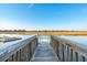 Scenic wooden dock leading to calm water and marshland under a clear blue sky at 1614 Teal Marsh Rd, Charleston, SC 29412