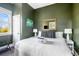 A queen sized bed with olive green walls, lamps, mirror, and artwork at 162 Spring St # D, Charleston, SC 29403