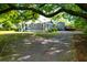 Charming gray home featuring a detached garage, and gravel driveway, all shaded by a large tree at 1637 Pinckney Park Dr, Charleston, SC 29407