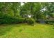 The landscaped backyard showcases a storage shed, trees, birdhouse and verdant lawn at 206 Brailsford Rd, Summerville, SC 29485