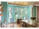 Inviting dining area with turquoise window frames offering views of the outdoors and wood dining table at 2114 Pettigrew St, Sullivans Island, SC 29482