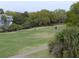 Scenic view of golf course, lush greenery, and a pond behind the home at 237 Driftwood Ln, Edisto Island, SC 29438