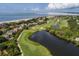 Scenic aerial view of a golf course community featuring lush fairways, a pond, and stunning waterfront homes at 2401 Racquet Club Dr, Seabrook Island, SC 29455