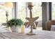 Stylish dining table decor featuring a starfish candle holder and lush green plant for a coastal atmosphere at 2401 Racquet Club Dr, Seabrook Island, SC 29455