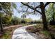 View of a landscaped walkway featuring an old oak tree, a flower bed, and a view of the tennis courts at 2401 Racquet Club Dr, Seabrook Island, SC 29455