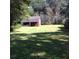 Large backyard with lush green grass, mature trees, and a storage shed at 32 Rosedale Dr, Charleston, SC 29407
