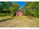 Charming red outbuilding with white trim, nestled in a green yard with mature trees under a bright blue sky at 32 Rosedale Dr, Charleston, SC 29407