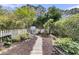 Secluded backyard with a charming stone path, mature trees, landscaping, and a white picket fence at 3372 Billings St, Mount Pleasant, SC 29466