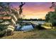 Beautiful backyard featuring a lighted tree, dock, and scenic waterfront views at sunset at 3610 Legareville Rd, Johns Island, SC 29455