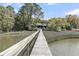 Picturesque view of a long dock surrounded by marshland leading to a beautiful house at 3610 Legareville Rd, Johns Island, SC 29455