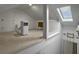 View of a carpeted attic featuring a skylight, small dresser, and white portable air conditioner at 411 Red Fox Run, Summerville, SC 29485