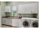 Bright laundry room featuring washer, dryer, storage cabinets, sink, and window that provides natural lighting at 421 Royal Assembly Dr, Charleston, SC 29492