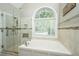 Bright bathroom with a garden tub, a glass shower, and a large window at 4403 Wild Thicket Ln, North Charleston, SC 29420