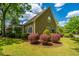 Charming home exterior with green lawn, red bushes, and mature trees under a sunny sky at 4403 Wild Thicket Ln, North Charleston, SC 29420