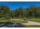Scenic view of a golf course with lush green grass, mature trees, and a golf cart on the path at 4403 Wild Thicket Ln, North Charleston, SC 29420