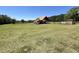 View of a horse barn with adjacent corrals in a large grassy field at 6935 Hickorynut Ln, Ravenel, SC 29470