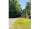 Long driveway approaching property with a wooden fence and dense trees at 6935 Hickorynut Ln, Ravenel, SC 29470