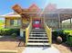 Stairs leading up to the log cabin with a red front door and wood railings at 6935 Hickorynut Ln, Ravenel, SC 29470