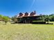 Charming log cabin home with red metal roof, dormers, covered porch, and landscaped yard at 6935 Hickorynut Ln, Ravenel, SC 29470