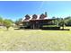 Exterior view of the charming log cabin home with a red metal roof and dormer windows at 6935 Hickorynut Ln, Ravenel, SC 29470