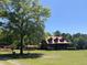 The cozy cabin-style home with a large tree in the front yard is set on vast, green acreage at 6935 Hickorynut Ln, Ravenel, SC 29470