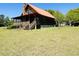 Exterior view of the log cabin home with a stone chimney and a red metal roof at 6935 Hickorynut Ln, Ravenel, SC 29470