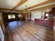 Bright, open living room with hardwood floors, stone fireplace, wooden beams, and kitchen access at 6935 Hickorynut Ln, Ravenel, SC 29470