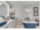 Elegant bathroom with double sinks, modern fixtures, white shaker cabinets, and a freestanding tub at 70 King St, Charleston, SC 29401
