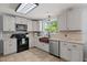 White kitchen features stainless steel appliances and granite countertops with tile floors at 8524 Belford Ct, North Charleston, SC 29420