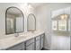 Dual-sink bathroom featuring a gray vanity, modern fixtures, and an open doorway to bedroom at 9428 Sweep Dr, Summerville, SC 29485