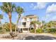 Exterior elevation of the 3 story home with white balconies and mature palm trees at 109 Carolina Blvd, Isle of Palms, SC 29451