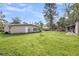 Spacious backyard with green grass, the house, and a shed in a tree-filled environment at 1239 Old Orchard Rd, Charleston, SC 29412