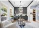Charming bar area with dark gray cabinets, wine storage, and two comfortable chairs near a sunlit window at 1440 Teaberry Path, Charleston, SC 29414