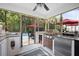 Screened-in outdoor kitchen with grill, mini fridge, and countertops overlooking the pool and greenery at 1440 Teaberry Path, Charleston, SC 29414