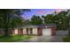 Dusk view of a brick home with an attached garage, featuring a quaint front porch and green lawn at 201 Judith Dr, Summerville, SC 29485