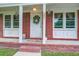 Close-up of charming brick front porch with decorative wreath, plants, and ample natural light at 201 Judith Dr, Summerville, SC 29485