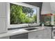 Close-up of a kitchen sink beneath a large window with views of lush greenery and dark backsplash at 2455 The Bent Twig, Seabrook Island, SC 29455
