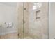 Glass-enclosed shower featuring natural stone tile, a rainfall showerhead, and built-in shelving at 2455 The Bent Twig, Seabrook Island, SC 29455