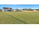 Large backyard with manicured lawn, wooden fence, and houses visible in the distance at 308 Cypress Branch Rd, Huger, SC 29450