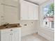 Well-lit laundry room with a sink, storage cabinets, and a window providing natural light and ventilation at 43 Montrose Rd, Mount Pleasant, SC 29464