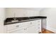 Wet bar with stainless steel refrigerator, stainless sink, black granite countertop, and white cabinets at 43 Montrose Rd, Mount Pleasant, SC 29464