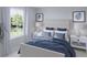 Cozy bedroom with white furniture, blue accents, bedside lamps, and natural light from the large window at 596 Red Monarch Way, Moncks Corner, SC 29461