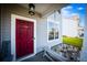 Inviting front porch with a red door, hanging light, white seating, and a small flower bed at 613 Ravens Wood Rd, Summerville, SC 29486