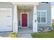 Welcoming front porch with a red door, white columns, bench seating, and decorative landscaping at 613 Ravens Wood Rd, Summerville, SC 29486