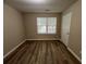 A bright bedroom featuring wood floors, a window, and a door, offering a comfortable living space at 9914 Levenshall Dr, Ladson, SC 29456