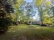 Expansive backyard with mature trees surrounding a brick home, offering a serene and private setting at 114 California Ave, Moncks Corner, SC 29461