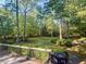 Serene backyard view from the deck, featuring mature trees, lush greenery, and a fire pit at 114 California Ave, Moncks Corner, SC 29461