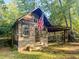 Charming cabin surrounded by trees featuring a small porch and an American flag at 114 California Ave, Moncks Corner, SC 29461