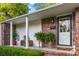Charming front porch features brick accents, ferns, and a stylish front door with glass and decorative wreath at 114 California Ave, Moncks Corner, SC 29461